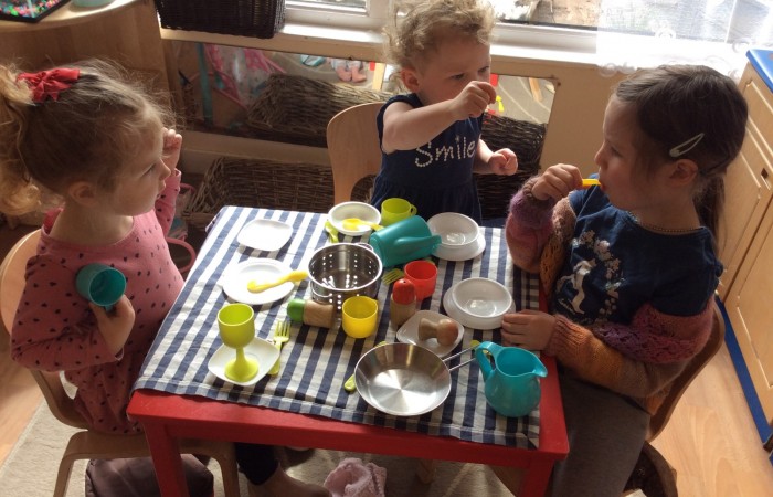 nursery children sit at a table and play with pretend food