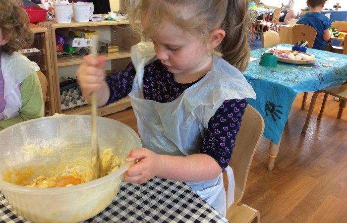 nursery child mixing ingredients in a bowl