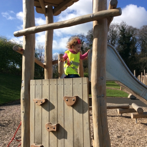 a nursery child plays on a slide with climbing wall